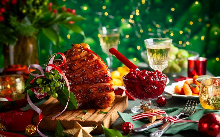 Glazed roast ham with cloves,sparkling wine and traditional vegetables dishes for Christmas dinner.